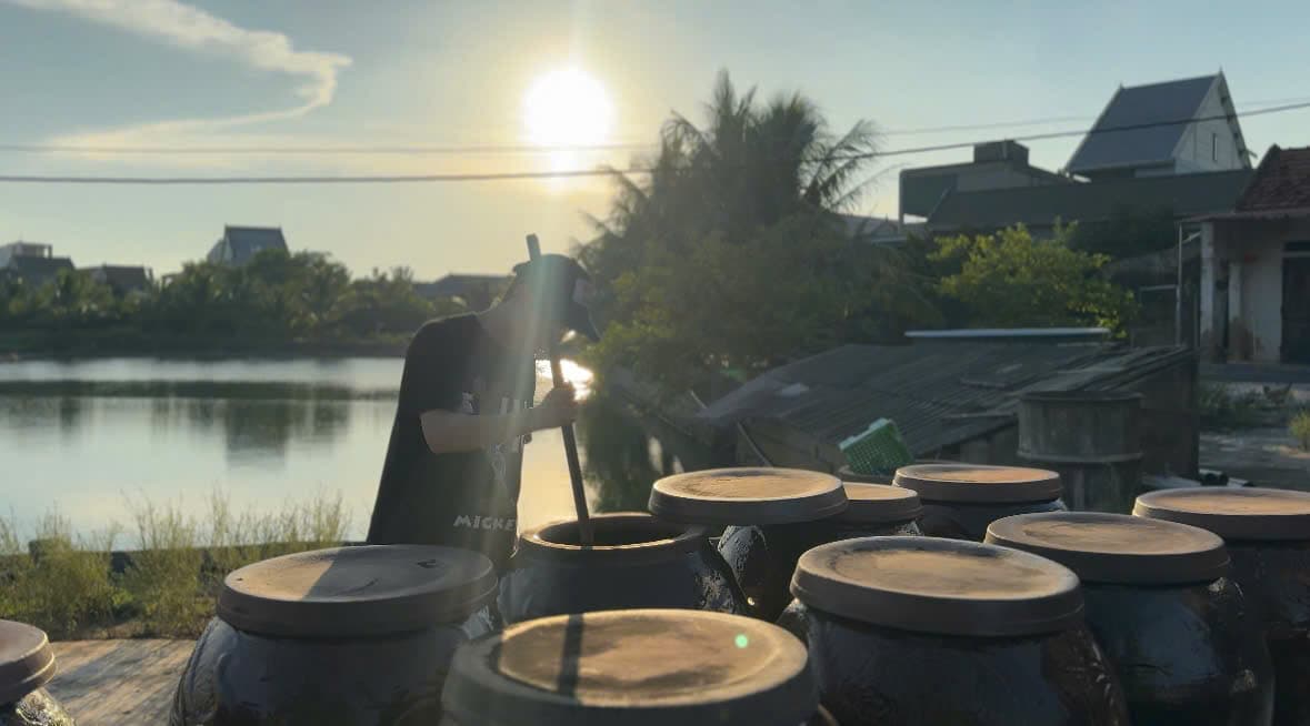 Thợ khuấy lu mắm dưới ánh hoàng hôn